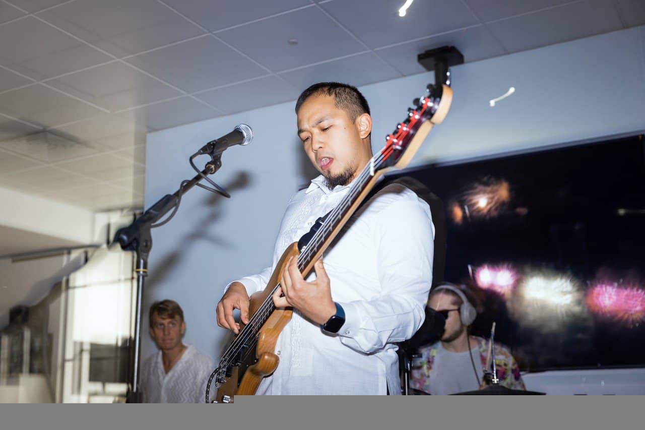 Pinoy scientist Gabriel Gallardo in a white shirt playing an electric bass guitar.