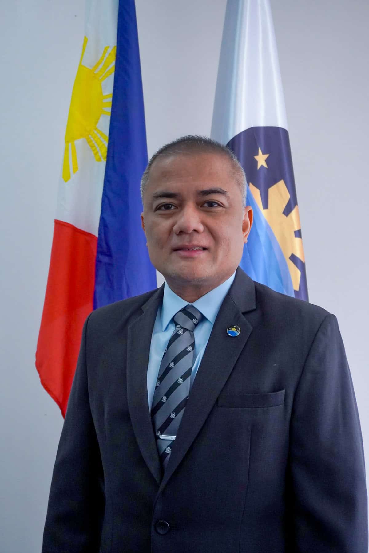 Dr. Joel Joseph S. Marciano, Jr. has short trimmed hair and is wearing a dark suit, striped tie, and a PhilSA pin.