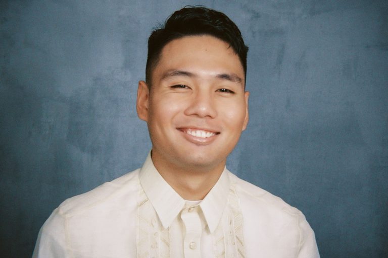 Pinoy Scientist Gregor Ethan Posadas has short dark hair, smiles at the camera, wearing a traditional Barong Tagalog shirt against a plain blue-gray background.