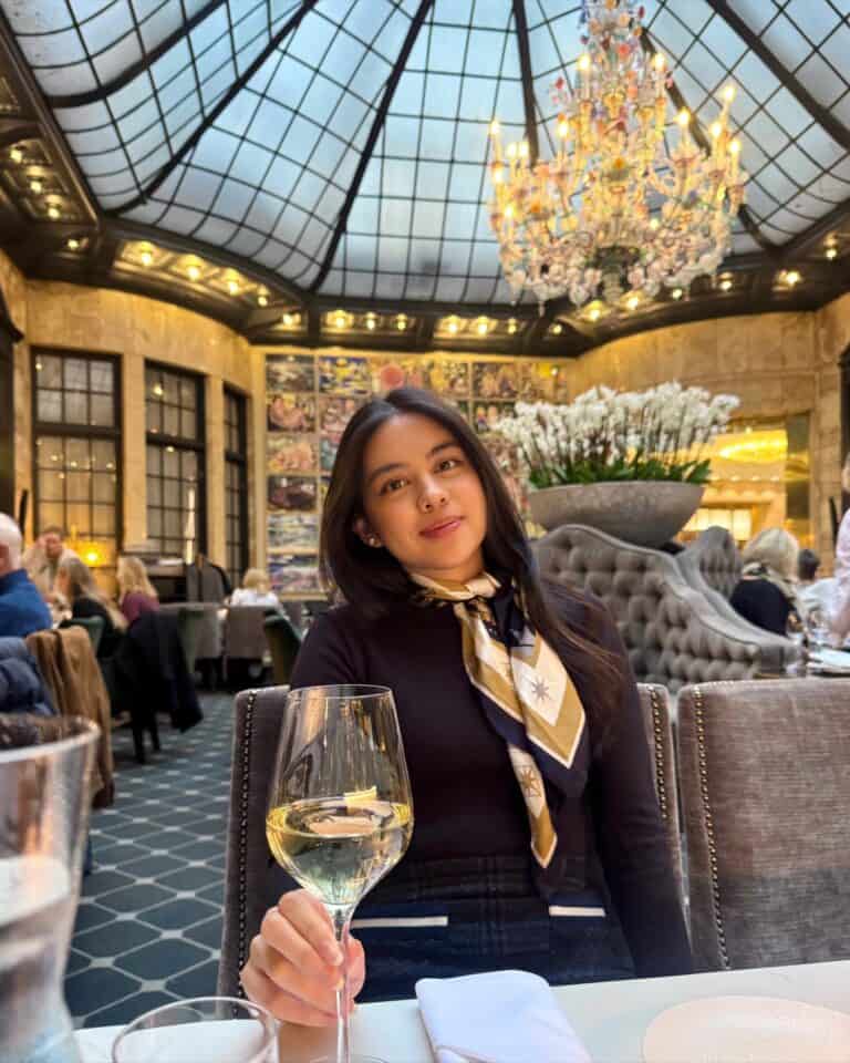Pinoy scientist Samantha Julia Eala sits at a restaurant table with a glass of white wine surrounded by elegant décor.