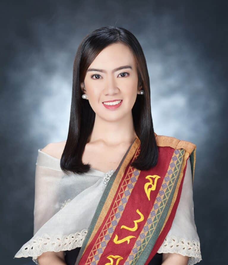 PInoy scientist Dr. Therese Anne Rollan-Soriano wearing sablay and a sheer, embroidered blouse, smiling in front of a gray studio background.