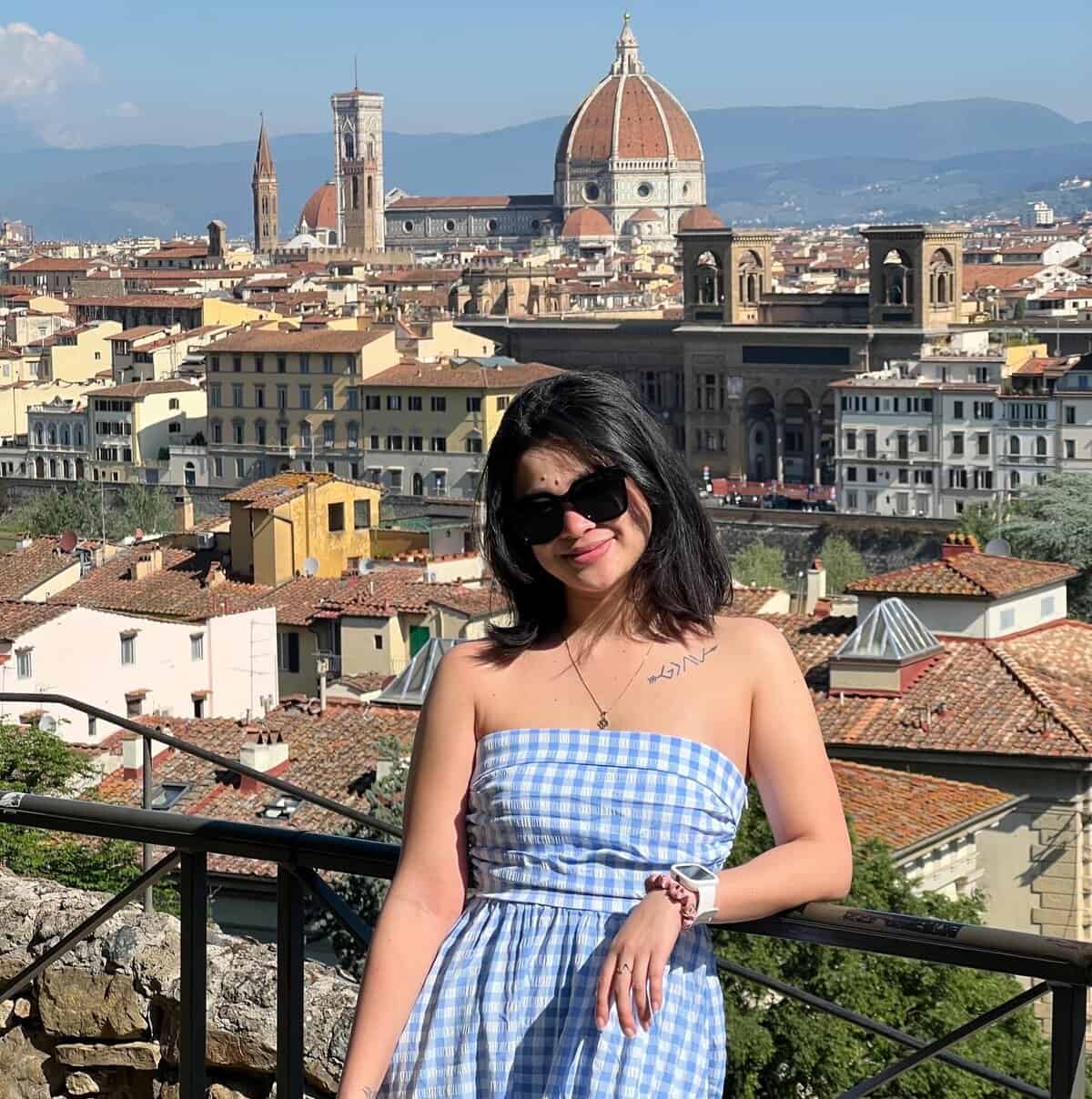 Pinoy scientist Anisa Pabingwit smiles in front of a scenic view of Florence, Italy, with the Florence Cathedral and city rooftops in the background on a sunny day.