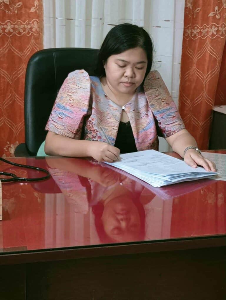 Pinoy scientist Dr. Natasha Benitez sits at a desk, reading and writing on documents.