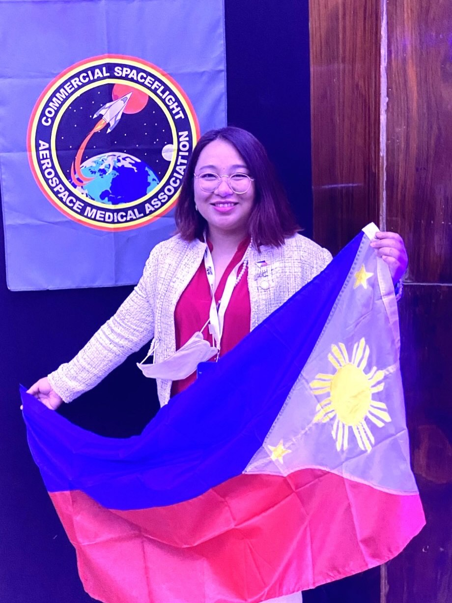 Pinoy scientist Catherine Mandigma smiling and holding the Philippine flag