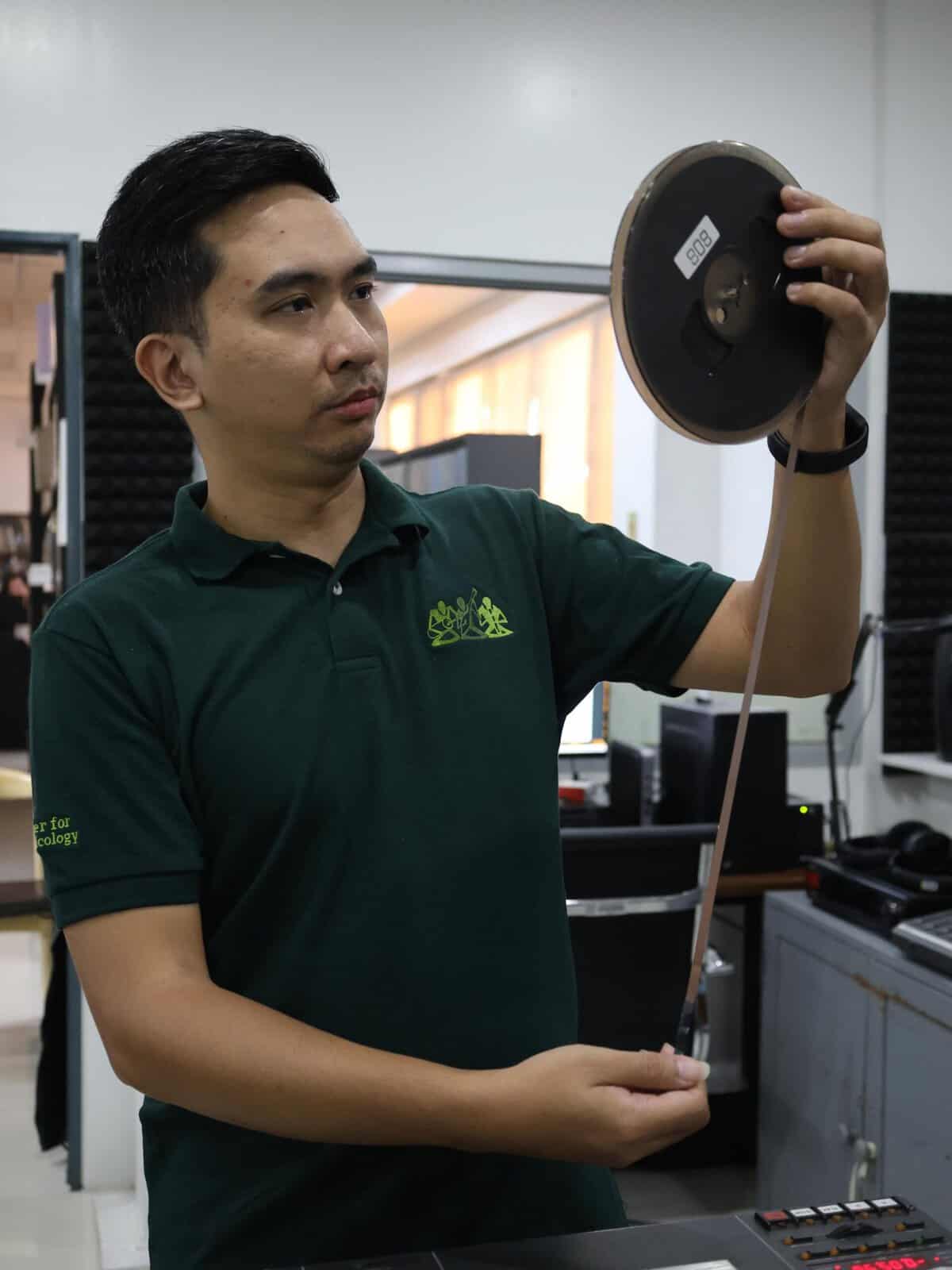 Ben Justine Velasco examines a reel of tape in a recording studio
