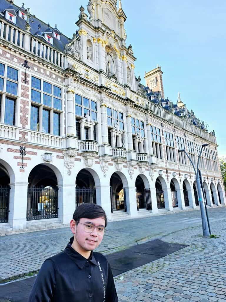 Pinoy scientist Jaro Garcia in black shirt standing in front of a large historic building with arched windows.