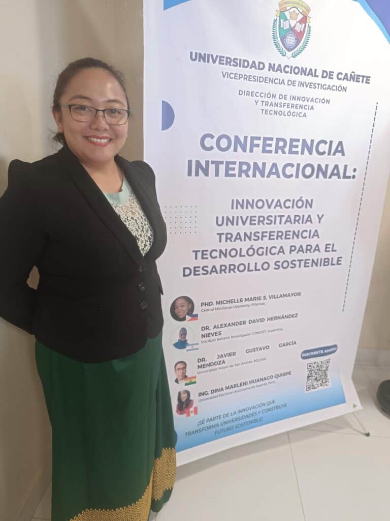 Pinoy scientist Michelle Marie Villamayor stands beside a conference banner about university technology and sustainability.