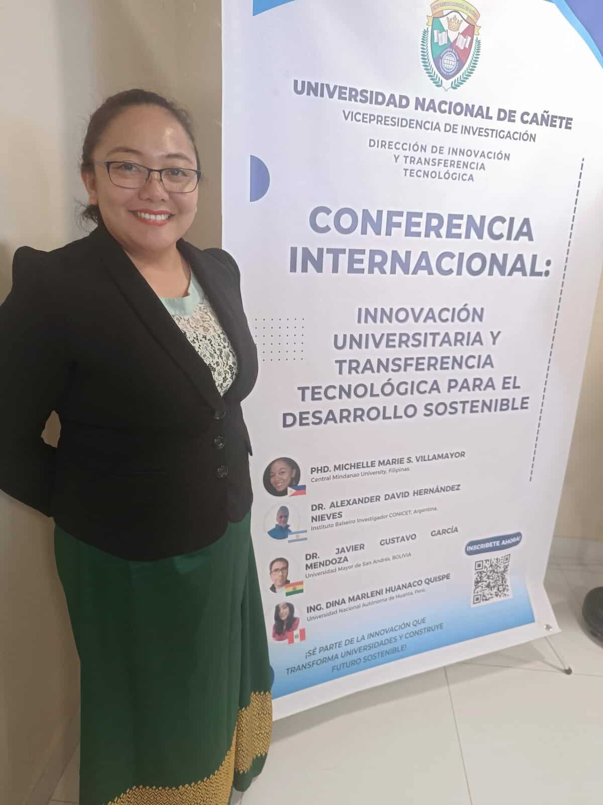 Pinoy scientist Michelle Marie Villamayor stands beside a conference banner about university technology and sustainability.