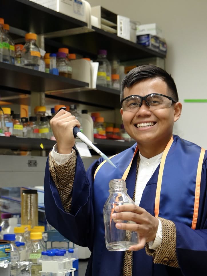 Pinoy scientist Jairus Meer smiling while using a pipette and clear bottle in a laboratory